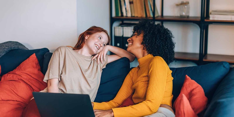 Two friends talking in a relaxed way in front of a laptop